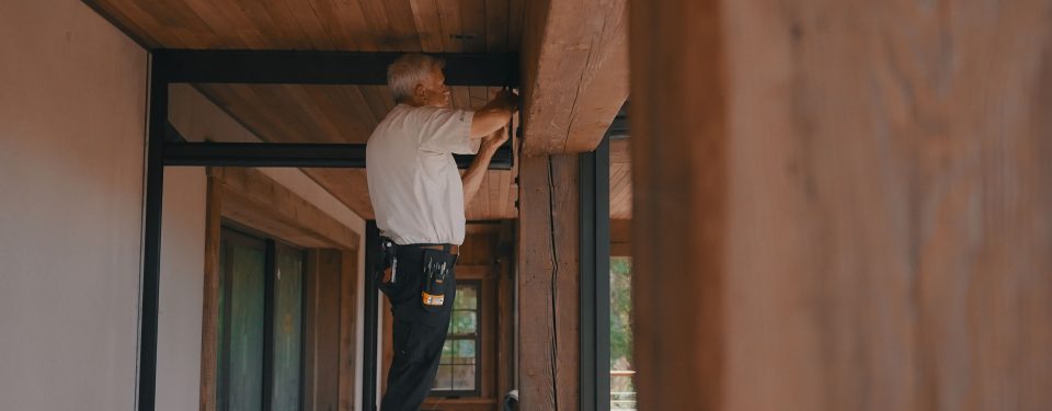 Man installation retractable motorized screens on patio